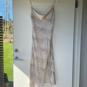 Långklänning med svart prickigt mönster från Gina Tricot - Säljer en snygg långklänning från Gina Tricot i ljus beige med svart prickigt mönster. Klänningen har smala axelband och en avslappnad passform, perfekt för varma dagar.