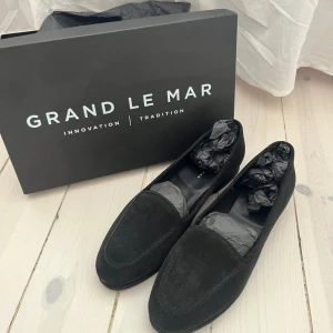 Svarta mockaloafers från Grand Le Mar - Stilrena svarta loafers i mocka från Grand Le Mar. Skorna har en klassisk design med rund tå och platt sula, perfekta för en dressad look men även riktigt schyssta till vardags! Använda 1 gång!!  Levereras med originalkartong.
