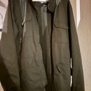 Olivgrön jacka från Elvine - Säljer en olivgrön jacka från Elvine med flera praktiska fickor framtill och dragkedja. Jackan har lång ärm och en stilren, enkel design som passar perfekt till vardags. Materialet känns slitstarkt och jackan har en rak passform. Ordinarie pris 2000kr. Köparen står för frakten
