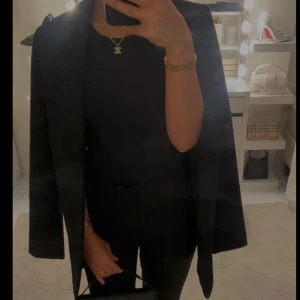 Svart kavaj - Snygg svart kavaj med klassisk design och knappar framtill. Perfekt för en stilren look. Långärmad med en rak passform som ger en elegant siluett. Använd endast en gång.