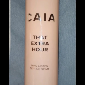 CAIA That Dewy Look Glow Setting Spray - Glow setting spray från CAIA som ger en fräsch och daggig finish. Perfekt för att fixera sminket och ge huden extra lyster. Kommer i en genomskinlig rosa flaska med vit text.