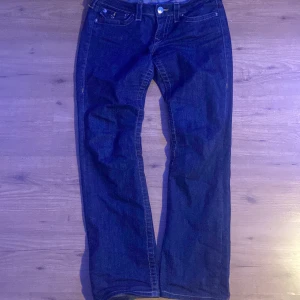 Mörkblå jeans från True Religion - Säljer ett par klassiska mörkblå jeans från True Religion med raka ben och ikoniska broderade bakfickor. Jeansen har normal passform och är tillverkade i kraftigt denimtyg. Mycket bra skick använda fåtal gånger! Pm för frågor 💕