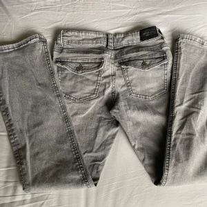  Grå Lågmidjade Jeans  - Grå bootcut jeans från Gina Tricot💗Bakfickorna är fint detaljerad med lock och knapp. Byxorna är knappt använda och har inga defekter. Strl är 40 men passar mig som använder 38(M). Midjemått:76runtom, Innerben:80cm, Längden:100cm 