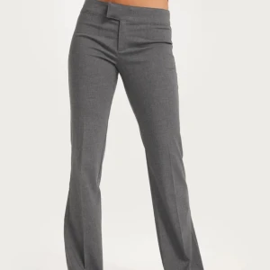 Grå kostymbyxor med rak passform - Snygga grå kostymbyxor med klassisk rak passform. Byxorna har låg midja och är perfekta för en stilren look. Använda några gånger och lite noppriga men väldigt fina. Köptes för 400 kr.
