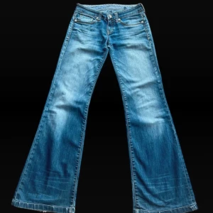 Blå bootcut jeans från Mavi - Säljer ett par klassiska blå bootcut jeans från Mavi med snygga slitningar och femficksmodell. Jeansen har normal passform och är tillverkade i mjukt denimtyg. Perfekta för dig som gillar en retroinspirerad look med utsvängda ben.