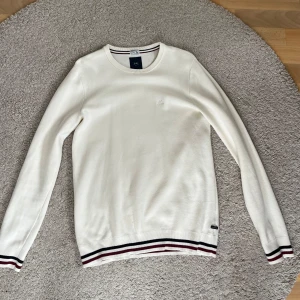 Vit tröja från Lindbergh - Säljer en stilren vit tröja från Lindbergh i storlek S. Tröjan har långa ärmar och ribbade muddar. Skick är 9/10 och tröjan är knappt använd. Pris kan diskuteras