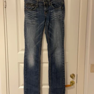 Low waist jeans  - Snygga blå jeansbyxor från Antique Rivet med slitningar och kontrastsömmar. Lågmidjade och strechiga, raka i benen.