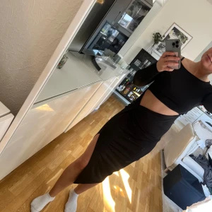 Svart ribbad långärmad klänning - Säljer en svart, tight och ribbad långärmad klänning i storlek XS. Klänningen har en kroppsnära passform och en slits på sidan, vilket ger en snygg siluett. Perfekt för dig som gillar stilrena och enkla plagg med en twist.