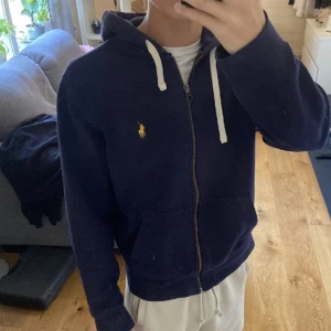 Ralph Lauren Ziphoodie - Mycket fint skick, inga defekter. Modellen på bilden är 180 cm. Storlek M passar dig som vanligtvis bär S eller M Kom gärna med prisförslag eller andra frågor!