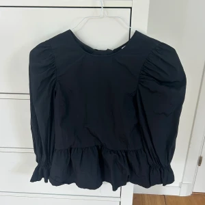 Svart blus - Svart blus med volanger och knytdetaljer från Divided Hm.