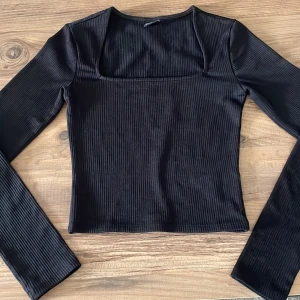 Svart ribbad långärmad topp - Snygg svart långärmad topp med fyrkantig ringning och ribbad struktur. 
