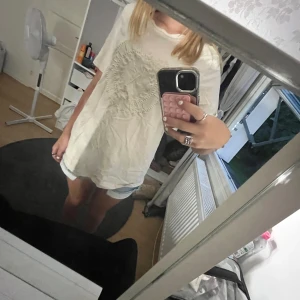 Vit oversized t-shirt med broderi - Säljer en vit oversized t-shirt med coolt broderat mönster framtill. T-shirten har korta ärmar och är gjord i mjuk bomull, perfekt för en chill och avslappnad stil. Passar dig som gillar en loose fit och vill ha något enkelt men ändå med en snygg detalj.