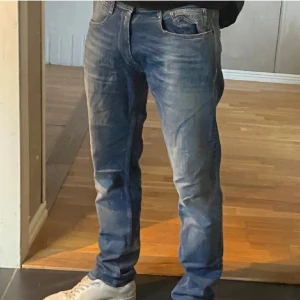 Blå Replay Anbass jeans straight fit - Säljer ett par blå Replay Anbass jeans med snygg tvätt och klassisk femficksdesign. Jeansen har rak passform och normal midja, tillverkade i mjukt denimtyg med lite stretch för extra komfort. Perfekta för dig som gillar en clean och tidlös look.