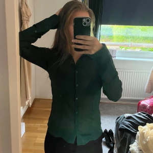 Mörkgrön tunn skjorta  - Snygg mörkgrön skjorta från BikBok i tunn, lätt transparent polyester. Klassisk krage, långa ärmar och knäppning framtill. Perfekt att styla med svarta byxor eller jeans. Säljer då den inte kommer till användning längre 💗💗