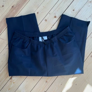 Mörkblå byxor med resårmidja - Mörkblå byxor med avslappnad passform och resår i midjan. Byxorna har två fickor framtill och är tillverkade i 100% polyester. Perfekta för en chill och bekväm stil.