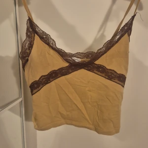 Beige linnetopp med brun spets  - 🌸Supersöt beige linnetopp från FB Sister i storlek XXS🌸. Toppen har tunna axelband och är dekorerad med brun spets längs urringningen och under bysten. Perfekt för lager på lager eller som statement-piece till jeans eller kjol. Somrig och härlig, fångar allas uppmärksamhet💐💐💐priset kan diskuteras♡