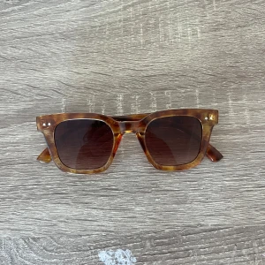 Brun mönstrade solglasögon från Glitter - Snygga solglasögon från Glitter med fyrkantig form och brunmelerad båge. Glasen är mörktonade och har inga tecken på skadning. Använd typ 2 gånger och funkar för både dam och herr skulle jag säga. 