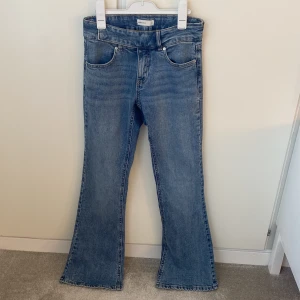 Lågmidjade blåa bootcut jeans  - Snygga blå bootcut jeans från Gina Tricot i storlek 34. Klassisk femficksmodell med normal midja och utsvängda ben. Jeansen är i ett mjukt denimtyg och har en längd på cirka 80 cm i innerben och midjemått på 36cm