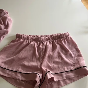 Rosa pyjamassrt från Anna Field - Mjukt och skönt rosa pyjamaset från Anna Field med elastisk midja och svarta detaljer längs kanterna. Inga snören i sidan då jag dragit ut dom och ej hittar de…. Inte använd mycket, nypris ca 350kr💞💞