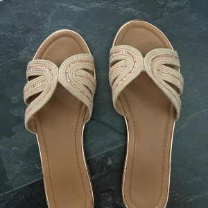 Beige sandaler med glitter - Snygga beige sandaler med flätade band och glittriga detaljer. Skorna är i storlek 40 och är ifrån Deichmann