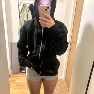 Svart oversized kofta med dragkedja - Svart kofta med huva och hel dragkedja framtill. Koftan har en loose passform och är tillverkad i mjukt bomullsmaterial. Perfekt för chill dagar eller när du vill ha en enkel och stilren look.