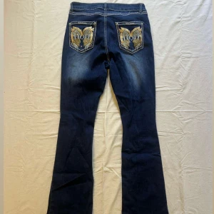 Mörkblå highwaist jeans - Mörkblp highwaist jeans med vingar på fickorna. Innerbenslängd: 80cm, midja: 37cm💙 