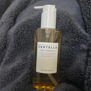 SKIN1004 Centella Cleansing Oil 200ml - Madagascar Centella Light Cleansing Oil från SKIN1004 är en lätt, gulaktig rengöringsolja med pumpflaska. Innehåller centella asiatica-extrakt och växtoljor som effektivt tar bort smink och orenheter.  Förpackningen är öppnad men har aldrig används. 