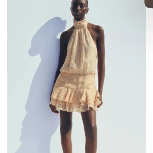 Blommig kortklänning med volang - Superfin klänning med volangkant nertill. Hög hals och ärmlös design. Perfekt nu i sommar. Ny med prislapp 