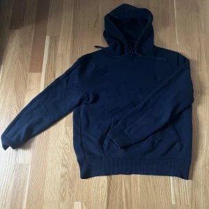 Ralph lauren hoodie - Mysig mörkblå stickad hoodie med huva och dragsko. Tröjan har långa ärmar och ribbade muddar vid ärmslut och nederkant. Perfekt för kyliga dagar när du vill vara både bekväm och snygg. Storlek M men sitter som S-M
