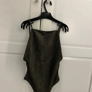 Fest topp  - Säljer en snygg glittrig svart body med smala axelband. enkel och stilren design, öppen rygg 