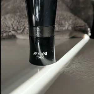 Armani Code herrparfym - Säljer en stilren och elegant herrparfym från Armani, modellen Code. Flaskan är svart med en glansig finish och har en modern, avsmalnande form. Perfekt för dig som gillar exklusiva dofter och snygg design.