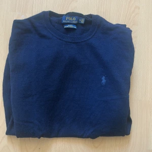 Mörkblå Merino tröja från Polo Ralph Lauren - Säljer en klassisk mörkblå merino tröja från Polo Ralph Lauren med rund halsringning och diskret broderad logga på bröstet. Perfekt till jeans eller chinos för en stilren look.