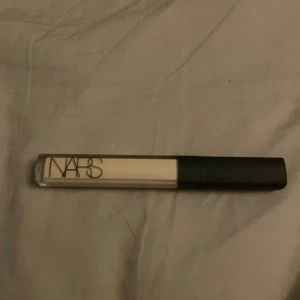 NARS Radiant Creamy Concealer i nyansen Chantilly - NARS Radiant Creamy Concealer i färgen Light 1 Chantilly. Kommer i en stilren, genomskinlig tub med svart lock och applikator. Perfekt för att ljusa upp under ögonen eller täcka ojämnheter. Ger en naturlig finish och är lätt att blanda ut.