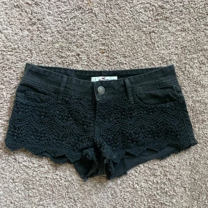 Svarta spetsdetaljerade jeansshorts från Hollister -  Midje måttet rakt över är 37 cm🥰 Supersnygga svarta jeansshorts från Hollister med dekorativ spets framtill. Modellen är lågmidjad och har råa kanter nertill för en cool look. Perfekta för sommaren och lätta att matcha med olika toppar.