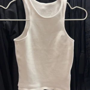 Vit ribbad linnetopp - Säljer en klassisk vit ribbad linnetopp med rund halsringning. Perfekt att styla till jeans eller kjol för en enkel och fräsch look.