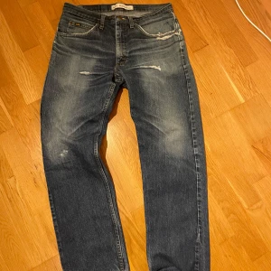 Blå jeans från Lee  - Blå jeans från Lee i modellen Regular Fit. Rak passform. Riktigt snygga slitningar och tvätt.