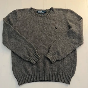 Grå stickad tröja från Polo Ralph Lauren - Klassisk grå stickad tröja från Polo Ralph Lauren med broderad logga på bröstet. 