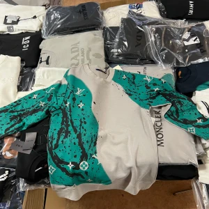 Louis Vuitton grå sweatshirt med grönt mönster - Säljer en grå sweatshirt från Louis Vuitton med unikt grönt och svart splash-mönster och klassiska LV-loggor. Tröjan är i 100% bomull och har rund hals och långa ärmar. Perfekt för dig som vill sticka ut med en exklusiv och trendig look.