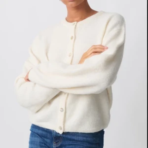 kofta - Supermjuk och fluffig krämvit kofta med rund halsringning och pärlemorknappar. Koftan har en loose passform och är stickad i ett gosigt material som passar perfekt till jeans eller kjol. nypris 399