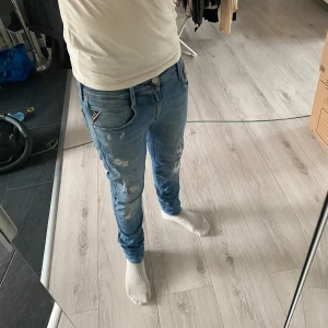 Replay Slimmade ljusblå jeans med stil av slitningar  - Säljer ett par ljusblå jeans med slitningar och snygga detaljer. Jeansen har smal passform och klassisk femficksdesign. Perfekta för dig som gillar en modern och avslappnad stil. Materialet är jeans och de har låg till normal midja.