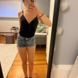 Jeansshorts med bling - Snygga blå jeansshorts med råa fransade kanter och massor av pärlor framtill. Klassisk femficksmodell med knapp och dragkedja. Perfekta för sommaren och ger en cool, trendig vibe till din outfit. 