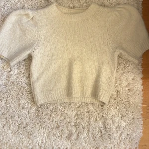 Beige stickad tröja från Vero Moda - Superfin beige stickad tröja från Vero Moda med kort puffärm och ribbade kanter. Tröjan är croppad och har en mjuk, mysig känsla som passar perfekt till höst och vinter. Enkel att matcha med både jeans och kjol. Orginalpris 300kr. Pris kan diskuteras 