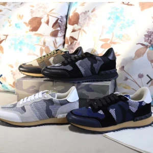Valentino Garavani Rockrunner sneakers - Snygga Valentino Garavani Rockrunner sneakers med svart och grått camouflagemönster. Skorna har detaljer i skinn och mocka, samt coola nitar på hälen. Klassisk snörning och platt sula ger en sportig vibe. Perfekta för dig som vill sticka ut med stil.