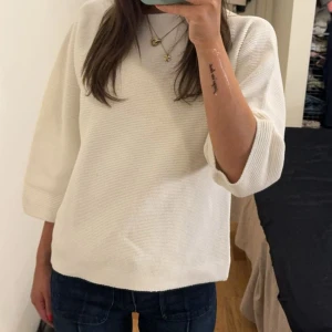 Vit stickad tröja med trekvartsärm - Superfin vit stickad tröja med trekvartsärmar och avslappnad passform. Tröjan har en enkel, stilren design och är perfekt att matcha med jeans eller kjol. Mjuk och skön, passar året runt för en clean look.