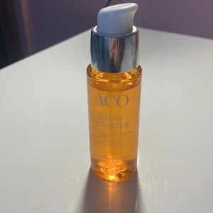 ACO Glow Booster serum 30ml - ACO Glow Booster är ett dag- och nattserum med C-vitamin och hyaluronsyra. Kommer i en snygg orange glasflaska med pump och silverdetalj. Ger glow och jämnar ut hudtonen. Perfekt för dig som vill boosta lystern i huden.