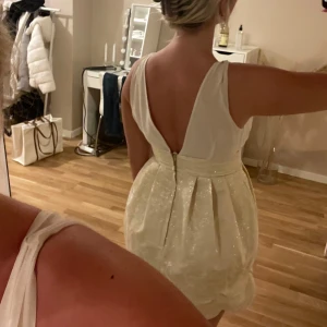 klänning - jättefin beige klänning med gulddetaljer från H&M! den är i väldigt bra skick utan defekter vad jag kan se. säljer pga att den är aningen för liten för mig