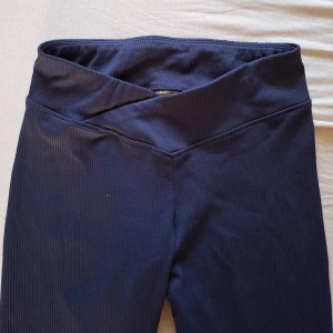 Mörkblå ribbade leggings H&M  - Snygga mörkblå ribbade leggings från H&M med omlott-detalj i midjan. De är stretchiga och sitter tight, perfekta för en chill vardagslook eller till träning. Tillverkade i mjuk polyesterblandning med elastan för extra komfort.
