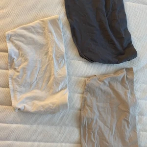 Tre enkla toppar i neutrala färger - Tre basic toppar i bomull. En är mörkgrå, en beige och en vit. Alla har en rak och enkel passform utan detaljer eller mönster. 