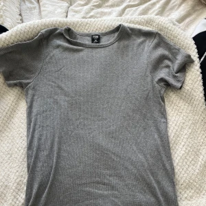 Grå ribbad t-shirt från FSBN - En enkel och stilren grå t-shirt från FSBN i ribbad bomull. Strl XL passar mer som L