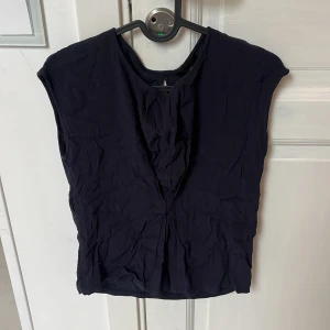 Svart blus från Massimo Dutti XS - Stilren svart blus från Massimo Dutti i storlek XS. Blusen har en enkel, rak passform med ärmlös design och diskret v-ringning framtill. Tillverkad i ett lätt och mjukt material som ger en snygg siluett. Perfekt att matcha med jeans eller kjol.